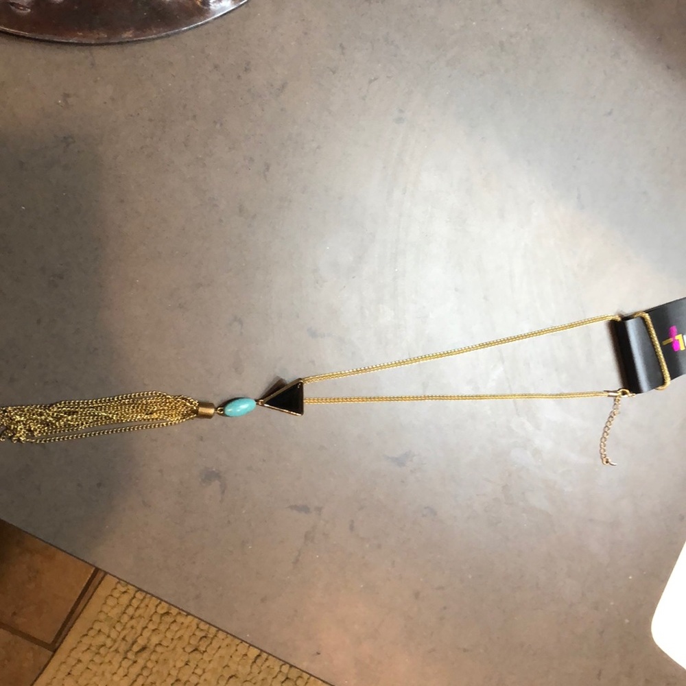 A gold necklace with a black triangle & blue stone